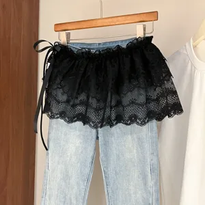 Vaqueros azul claro con falda de volantes de encaje negro, diseño en capas elegante.