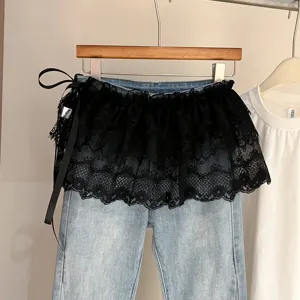 Vista detallada de los elegantes vaqueros azul claro con volantes de encaje negro y lazo.