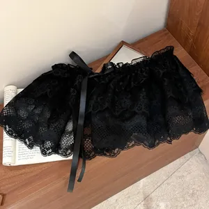 Primer plano detallado del elegante cuello de encaje negro con motivos florales y lazo.