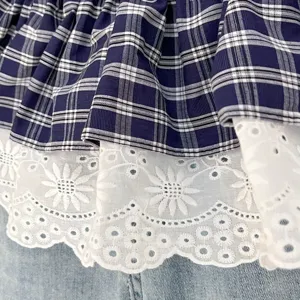 Detailed view of women's navy blue plaid layered skirt with delicate white floral lace hem.