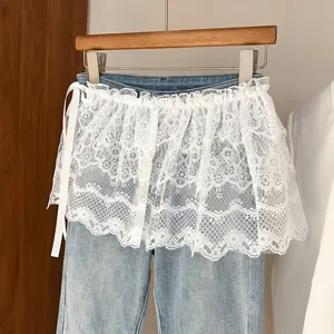 Vista detallada de vaqueros azules con delicada falda superpuesta de encaje blanco.