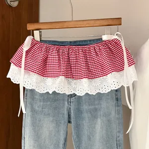 Close up view of red plaid and white lace skirt extender featuring side ribbons and denim waistband.