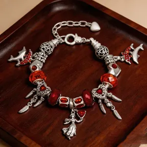 Detailaufnahme des silbernen DIY-Charm-Armbands mit roten Kristallen und Anhängern.