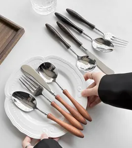 Dettaglio posate in acciaio inox con manico in legno cucchiaio e forchetta per la tavola.