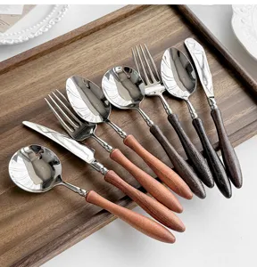 Dettaglio di posate in acciaio inossidabile con manico in legno, cucchiaio, forchetta e coltello.