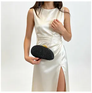 Détail d'une pochette de soirée noire en strass étincelante avec une bandoulière chaîne dorée.