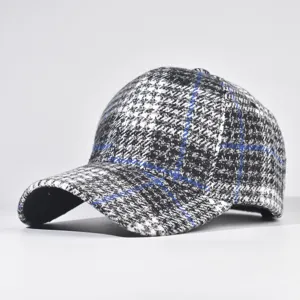 Close-up detail of black and white tweed baseball cap featuring blue grid lines.
