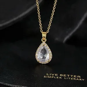 Close-up of sparkling teardrop zircon pendant necklace in gold tone, elegant jewelry detail.
