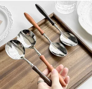 Cucchiaio da cucina in acciaio inossidabile con manico in legno, vista dettagliata.