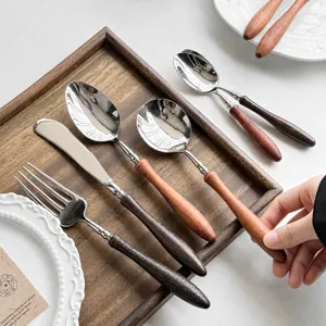 Set di posate in acciaio inossidabile con manico in legno, forchetta, cucchiaio e coltello.
