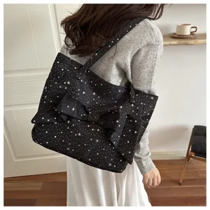 Dettaglio borsa tote con stampa stelle e fiocco indossata a spalla in ambiente chic.
