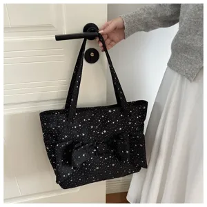 Vista dettagliata di una borsa tote in tela nera con stampa di stelle e un grande fiocco.