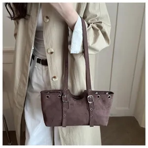 Stylische braune Wildleder Damen Umhängetasche mit Metallösen und doppelten Schnallenriemen.