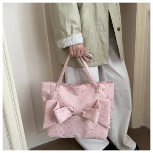 Primo piano della borsa tote in tela rosa con fiocco carino e motivi di stelle lucide.