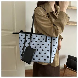 Borsa shopper azzurro chiaro a pois neri con pochette abbinata in una scena quotidiana.