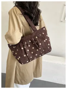 Vista dettagliata della borsa tote marrone a pois rétro portata a spalla, stile casual.