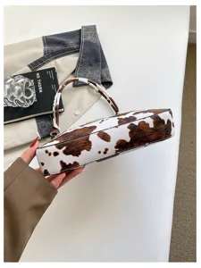 Primo piano della borsa a tracolla retrò con stampa mucca, mostra texture e design elegante.