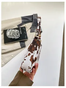 Dettaglio borsa a spalla con stampa mucca marrone e bianca, elegante borsa sottoascella in PU.