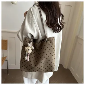 Vista dettagliata della borsa tote in tela a pois marroni con un simpatico ciondolo orsetto.