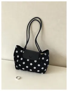 Black and white polka dot canvas shoulder bag with black leather flap and thin straps detail.