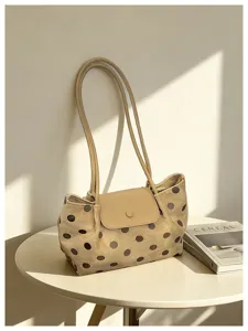 Detailed shot of a chic polka dot shoulder bag placed on a modern table with a magazine.