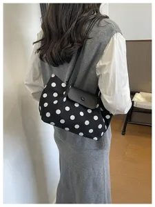 Detail shot of a chic black and white polka dot canvas shoulder bag worn by a model indoors.