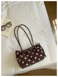 Brown polka dot shoulder bag with suede texture, thin straps and flap closure detail.