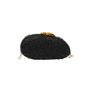 Détail de pochette de soirée noire, brillants strass et fermoir en métal doré.