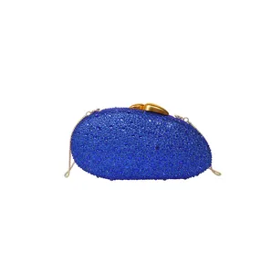 Détail de pochette de soirée en strass bleus, surface en cristal scintillant, chaîne dorée.