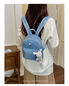 Detail view of stylish blue denim mini backpack with cute bear keychain and zipper pocket.