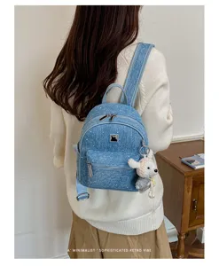 Detailed view of stylish denim mini backpack featuring cute bear pendant and metal buckle.