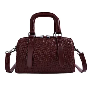 Detailopname van de bordeauxrode geweven PU-lederen tonvormige tas met fijne accenten.
