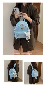 Detail shot of the light blue denim mini backpack with glitter and a cute knit bear pendant.