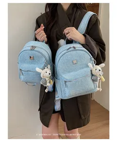 Detailed view of casual light blue denim backpack with cute rabbit charm and star pattern.