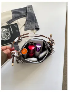 Vista dettagliata dell'interno borsa a tracolla con stampa mucca che mostra telefono e cosmetici.