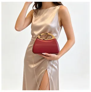 Red hard shell evening clutch bag with gold metal handle and chain strap for women.
