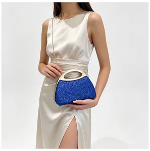Close-up detail of blue rhinestone evening bag with metallic handle and delicate chain strap.