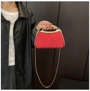 Detail view of the red rhinestone evening bag featuring a sleek metal handle and chain strap.