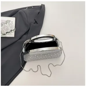 Detailed close-up of a sparkling rhinestone evening clutch bag with chic metal handle and strap.