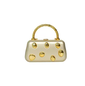 Gold metallic hard shell clutch bag luxury evening handbag with textured handle and pebbles.
