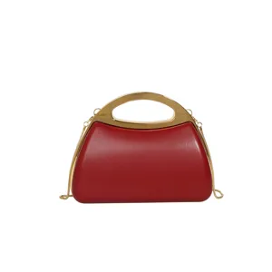 Elegant red hard-shell evening clutch bag with gold rigid handle and chain detail close-up.