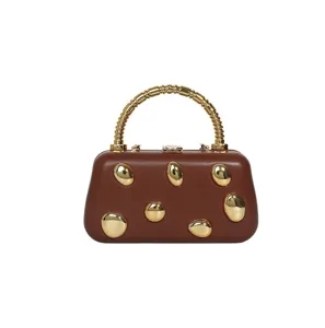 Detail view of the brown hard-shell evening clutch with gold metallic pebbles and handle.