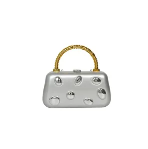 Silver metallic evening clutch detail showcasing unique 3D pebble studs and gold handle.