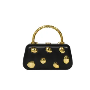 Black hard shell evening clutch bag with gold irregular pebble studs and metal handle main view