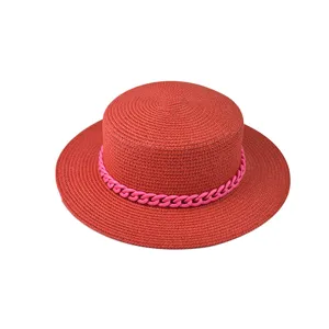 Detailansicht eines stilvollen roten Strohhutes mit trendiger rosa Kette für den Sommer.