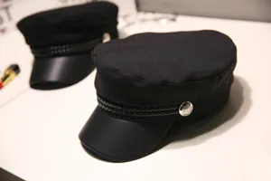 Details of black vintage newsboy hat with leather brim and chic braided band for retro outfit.