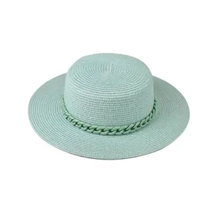 Detailaufnahme des hellgrünen Strohhatts mit modischem Kettenband für den Sommer am Strand.