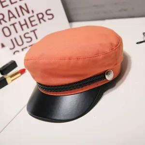 Chic orange women baker boy hat with black leather visor and stylish braided trim detail.