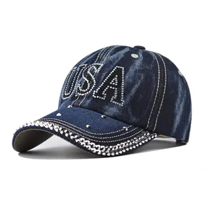 Vue détaillée d'une casquette en jean bleue avec lettres USA en strass et bord étincelant.