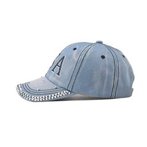 Gros plan casquette de baseball en jean bleu clair avec lettres USA en strass et visière cloutée.